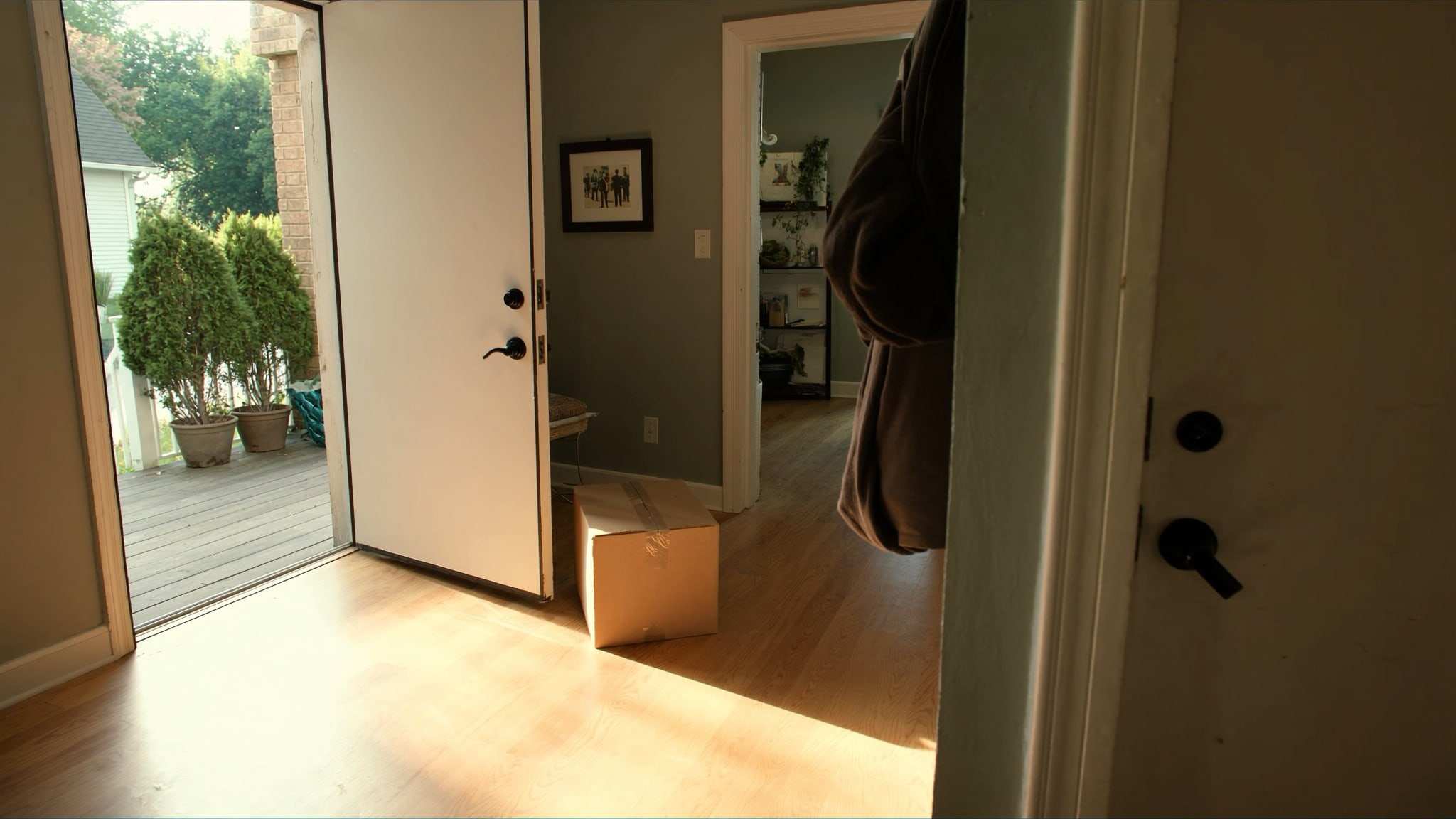 Front hallway of an older home with the door open to the porch and a packed box