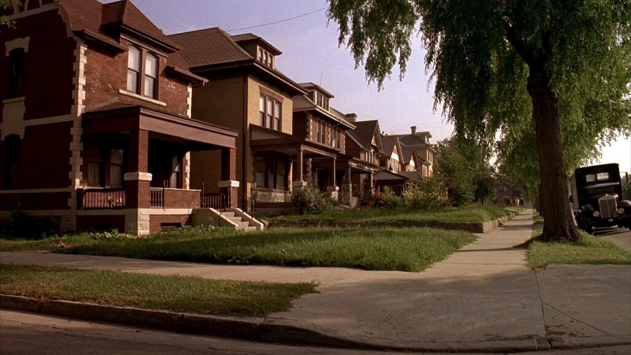 Row of early-1900s brick homes with front porches on a residential street