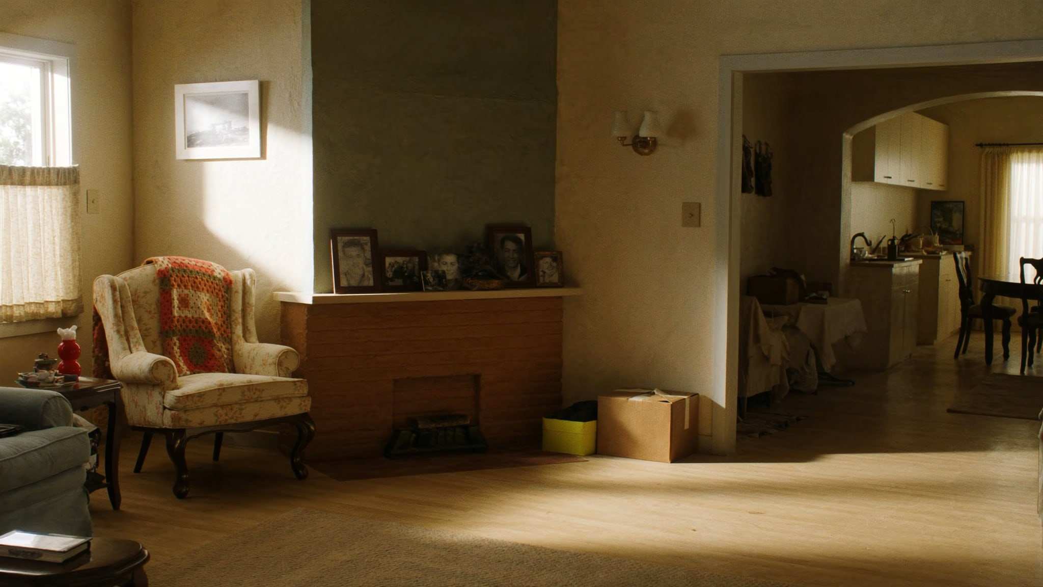 Sunny living room in an older home with family photos on the mantel and packed boxes