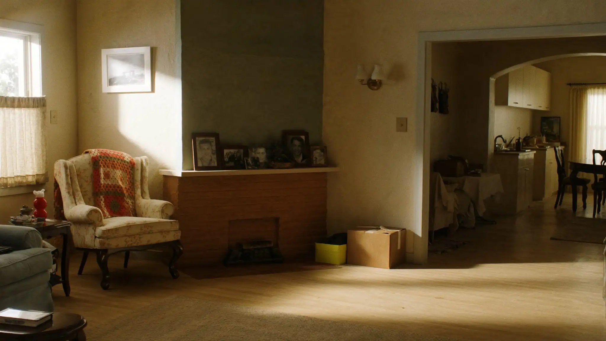 Sunny living room in an older home with family photos on the mantel and packed boxes